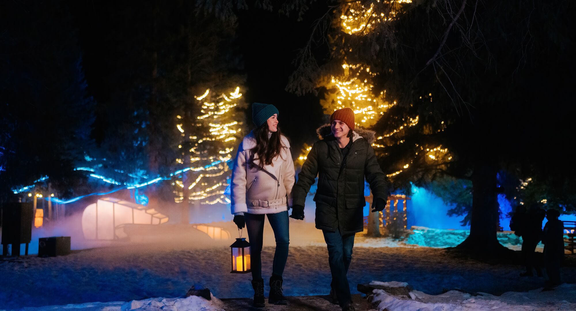 A couple walking through a lit up Cascade of Times Garden for In Search of Christmas Spirit in Banff
